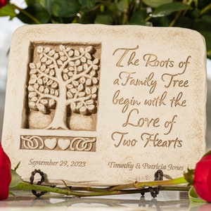 May include: A beige stone plaque with a carved tree design and the text "The Roots of a Family Tree begin with the Love of Two Hearts". The plaque also includes the date "September 29, 2023" and the names "Timothy & Patricia Jones".