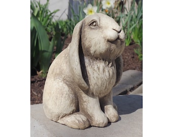 May include: A white and brown ceramic rabbit statue with long floppy ears. The rabbit is sitting with its head tilted up and its eyes closed.