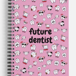 K&ouml;nnte beinhalten: Rosa gebundenes Notizbuch mit einem wei&szlig;en Hintergrund und einem Muster aus Cartoon-Z&auml;hnen mit verschiedenen Ausdr&uuml;cken. Der Text "future dentist" ist in Schwarz auf dem Einband gedruckt.