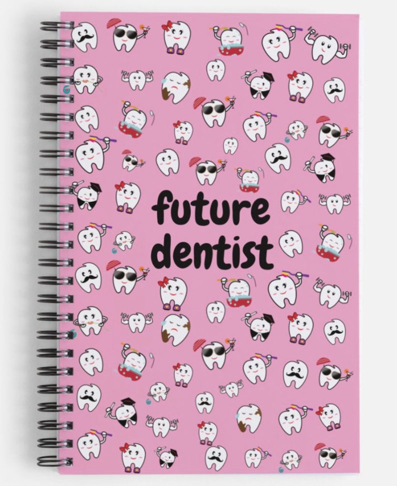 K&ouml;nnte beinhalten: Rosa gebundenes Notizbuch mit einem wei&szlig;en Hintergrund und einem Muster aus Cartoon-Z&auml;hnen mit verschiedenen Ausdr&uuml;cken. Der Text "future dentist" ist in Schwarz auf dem Einband gedruckt.