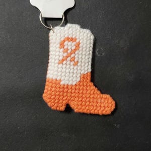 May include: Orange and white crocheted boot keychain with a white letter "P" on the front.