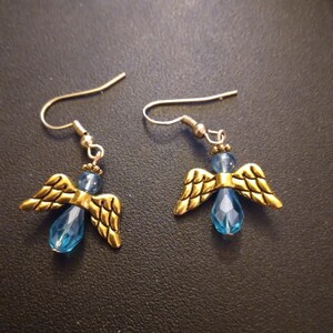 May include: A pair of gold angel wing earrings with blue crystal accents.