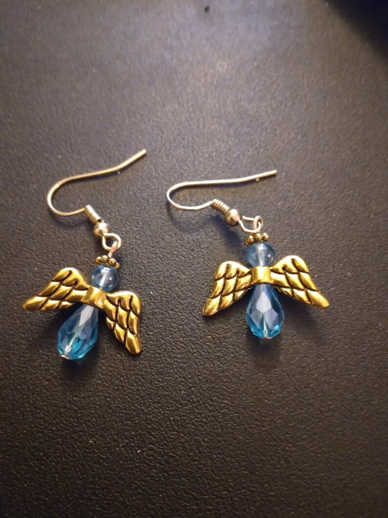 May include: A pair of gold angel wing earrings with blue crystal accents.