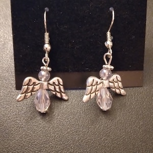 May include: A pair of silver angel earrings with clear crystal accents.