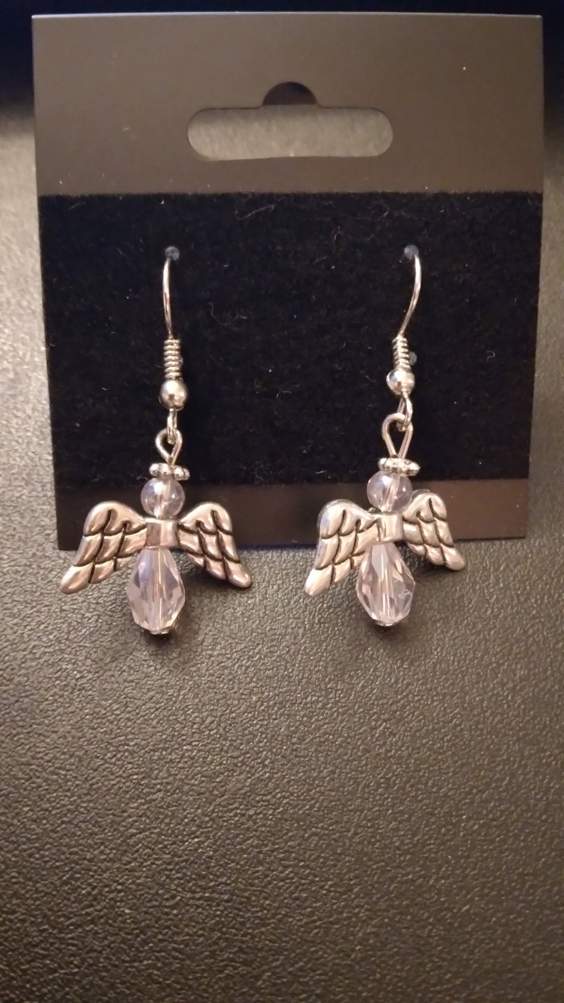 May include: A pair of silver angel earrings with clear crystal accents.