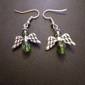 May include: A pair of silver angel wing earrings with green crystal beads.