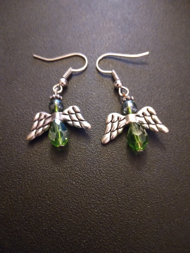 May include: A pair of silver angel wing earrings with green crystal beads.