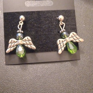 May include: A pair of silver angel wing earrings with green crystal accents.