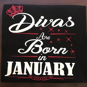 May include: Black t-shirt with white text that reads "Divas Are Born in January" with a red crown at the top.