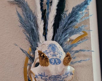 Espejo con decoupage de cráneo de cabra de origen ético, decorado con botánicos azules secos y plumas.