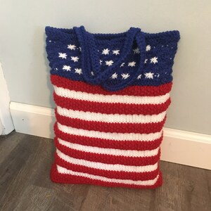 May include: A knitted tote bag with red and white stripes and a blue star-spangled section. The bag has two handles.