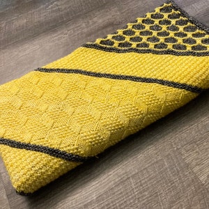 May include: A yellow and black knitted throw blanket with a honeycomb pattern on one end.