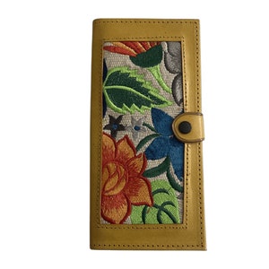 May include: A yellow leather wallet with a floral embroidered design. The embroidery features a variety of colors, including red, orange, yellow, green, blue, and white.
