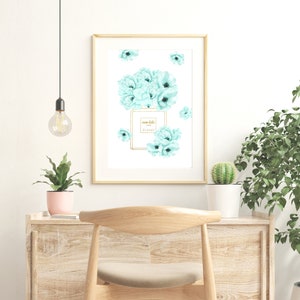 May include: A framed print with a watercolor illustration of a perfume bottle surrounded by light blue flowers. The bottle has the text "mon bebe" and "Paris" on it.