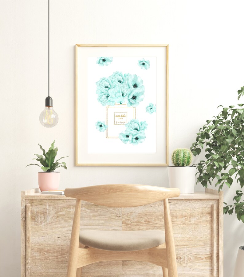 May include: A framed print with a watercolor illustration of a perfume bottle surrounded by light blue flowers. The bottle has the text "mon bebe" and "Paris" on it.