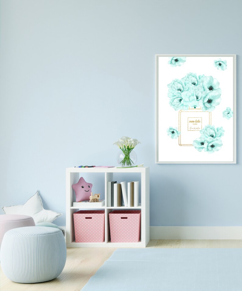 May include: A white framed print with a watercolor illustration of a perfume bottle and light blue flowers. The bottle has gold accents and the text "mon bebe Paris Eau de Parfum" on the label.