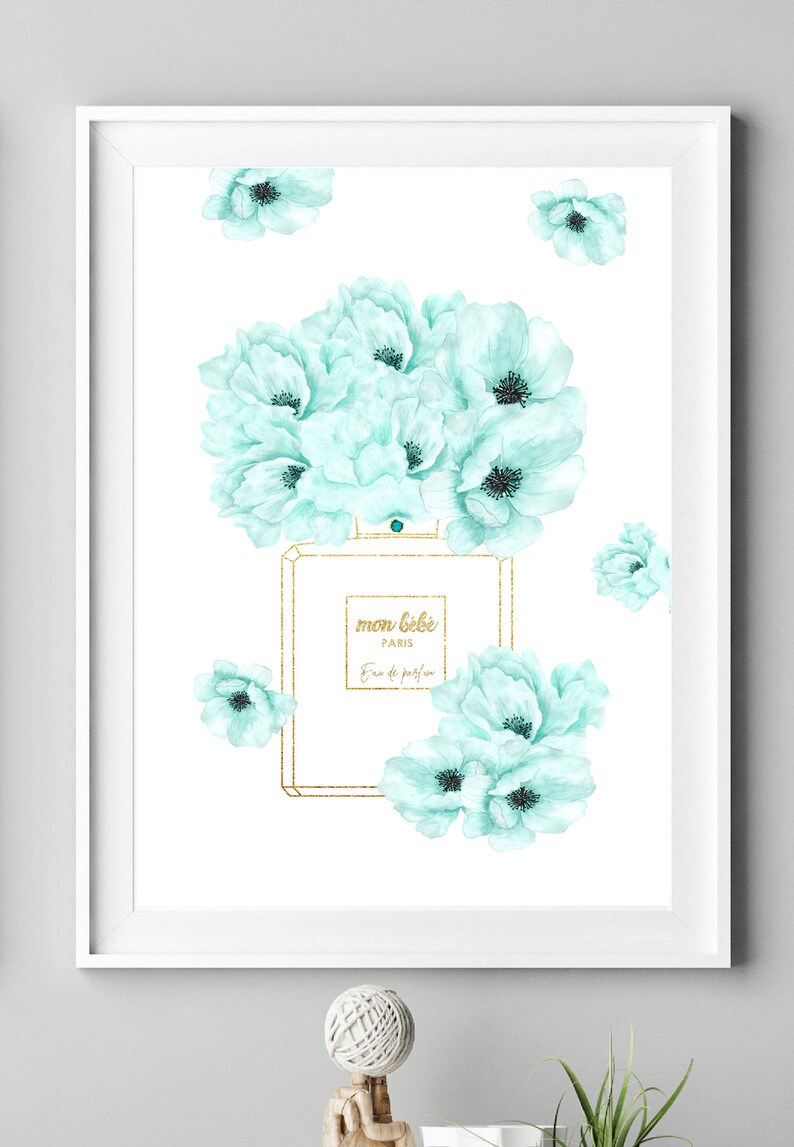 May include: A white framed print with a watercolor illustration of a perfume bottle with a gold lid and a bouquet of light blue flowers. The bottle has the text "mon b&eacute;b&eacute; PARIS Eau de parfum" on the label.