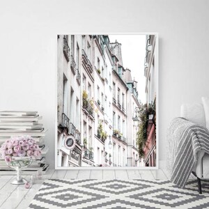 May include: A black and white photo of a narrow street in Paris, France. The street is lined with tall, white buildings with balconies and windows. The buildings are in focus, while the street is blurred in the background.