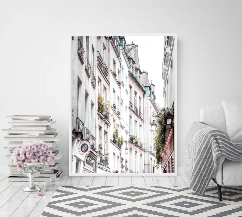 May include: A black and white photo of a narrow street in Paris, France. The street is lined with tall, white buildings with balconies and windows. The buildings are in focus, while the street is blurred in the background.