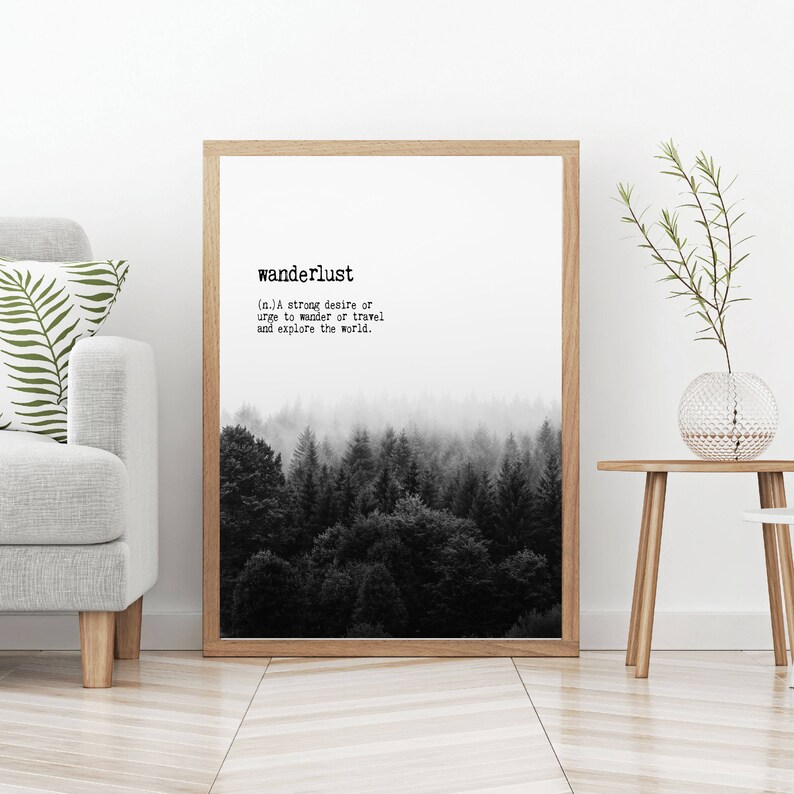 May include: Black and white print with the word "wanderlust" and its definition: "(n.) A strong desire or urge to wander or travel and explore the world." The print features a black and white image of a foggy forest.