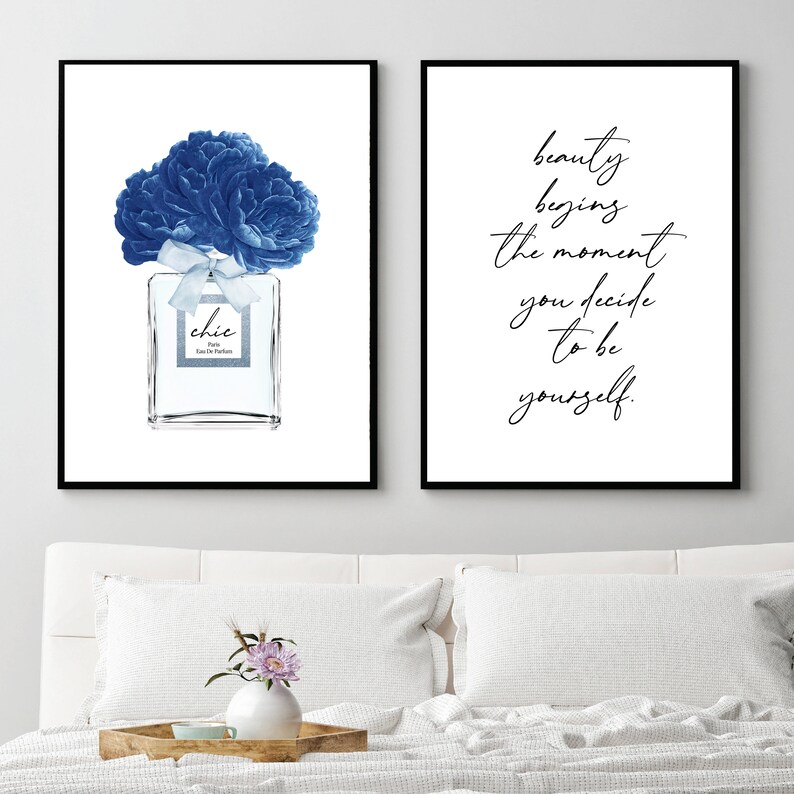 Op de afbeelding: Twee ingelijste prints, een met een blauwe bloemillustratie van een parfumfles met het woord "chic" op het etiket, en de andere met de tekst "schoonheid begint op het moment dat je besluit om jezelf te zijn."