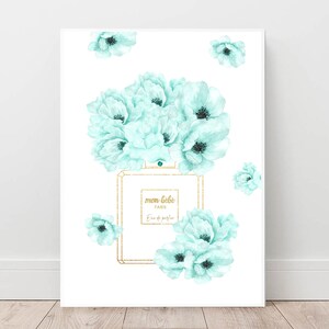 May include: A white background with a light blue watercolor floral design and a gold framed perfume bottle with the text "mon bebe PARIS Eau de parfum" on the label.