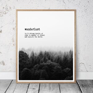 May include: Black and white print of a forest with the definition of the word "wanderlust" printed above the image. The definition reads: "(n.) A strong desire or urge to wander or travel and explore the world."