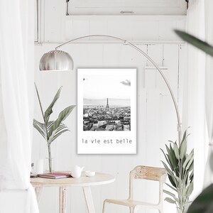 May include: Black and white photograph of the Eiffel Tower and the city of Paris. The text "la vie est belle" is printed below the image.