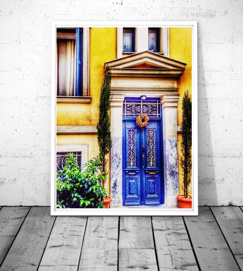 May include: A blue wooden door with intricate ironwork and a wreath on a yellow building with a white frame.
