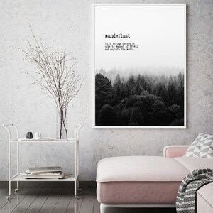 May include: A black and white print with the word "wanderlust" defined as a strong desire to travel and explore the world. The print features a foggy forest scene.