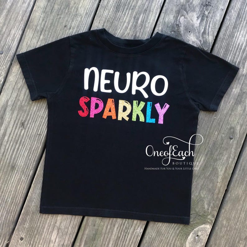May include: Black t-shirt with the text "NEURO SPARKLY" in rainbow colours.