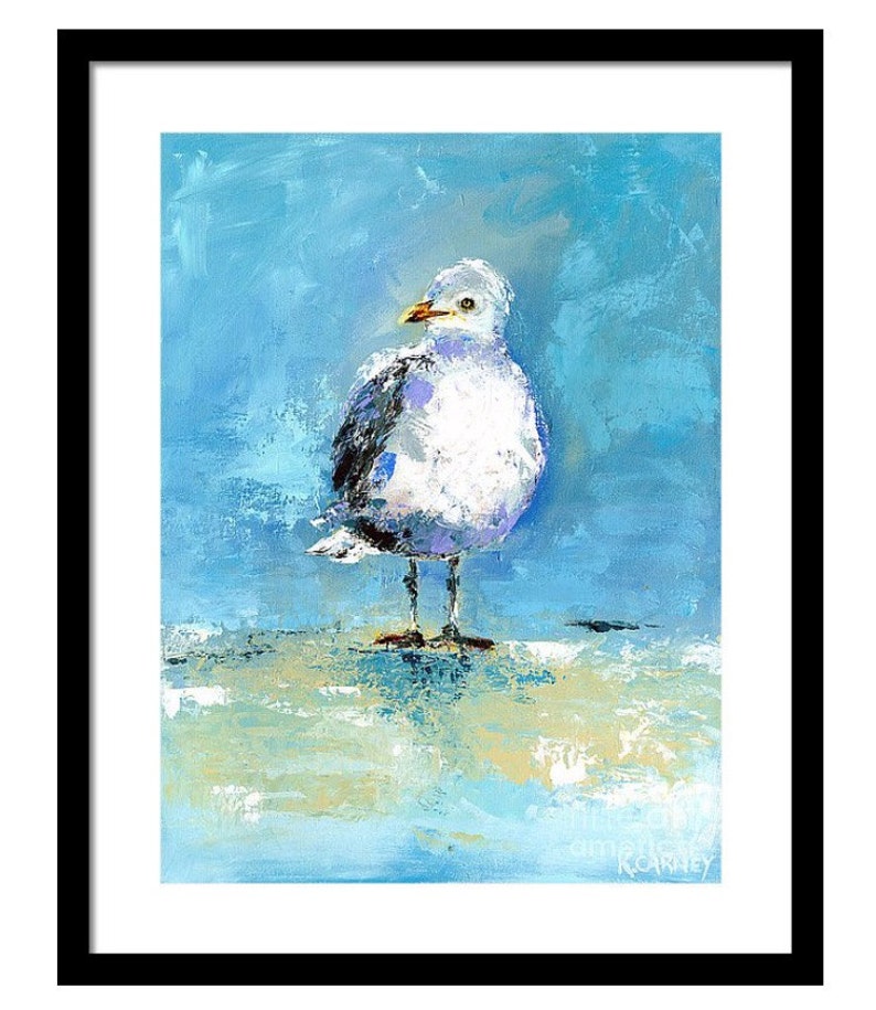 May include: An oil painting of a seagull with white, gray, and black feathers, standing on a light-colored surface. The background is a textured blue, and the artwork is framed in black. The seagull has a yellow beak and is looking to the side.