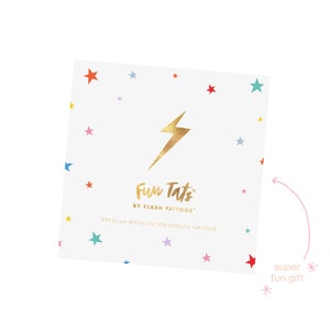 May include: A white card with a gold lightning bolt and the text "Fun Tats by Flash Tattoos" and "Premium Metallic Temporary Tattoos". The card is decorated with colorful stars.