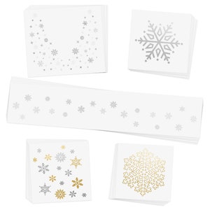 Op de afbeelding: Een set met sneeuwvlok stickers in zilver en goud. De stickers zijn in stapels van verschillende groottes en ontwerpen, waaronder een grote sneeuwvlok, een kleine sneeuwvlok en een rand van kleine sneeuwvlokken.