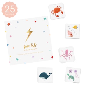 May include: A set of 25 temporary tattoos featuring a variety of sea creatures, including a crab, a fish, an octopus, a whale, a turtle, and a jellyfish. The tattoos are metallic and come in a variety of colors, including pink, blue, orange, and green. The tattoos are packaged in a white square box with a gold lightning bolt and the text "Fun Tats by Flash Tattoos" and "Premium Metallic Temporary Tattoos".