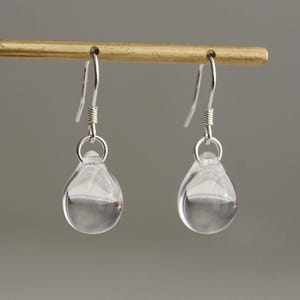 May include: A pair of silver teardrop earrings with clear glass drops.