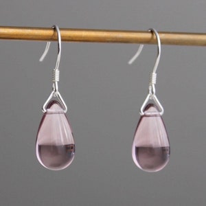 May include: A pair of silver dangle earrings with teardrop-shaped pink glass beads.