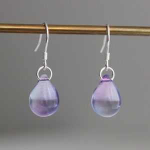 May include: A pair of silver teardrop earrings with purple and blue glass drops.