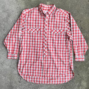 May include: A red and grey plaid long-sleeved button-down shirt with two chest pockets.