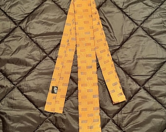 May include: A brown and orange patterned silk tie with a black label that says "Alfred".