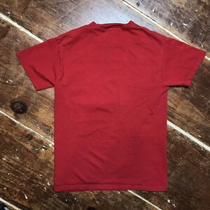 May include: A plain red t-shirt with short sleeves.