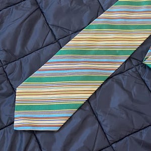 May include: A striped tie with a light blue, green, yellow, and red pattern. The tie is made of a silky material.