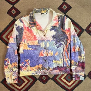 Peut inclure: Une veste boutonnée blanche avec une peinture colorée d'un paysage marin avec des voiliers et des arbres. La peinture est dans un style qui rappelle l'impressionnisme.