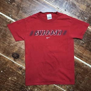 May include: Red short-sleeved t-shirt with a white "SWOOSH" graphic and a white Nike swoosh logo.