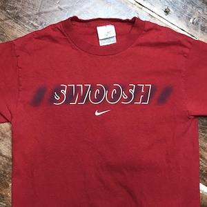 May include: Red t-shirt with a white "SWOOSH" graphic and a small Nike logo.