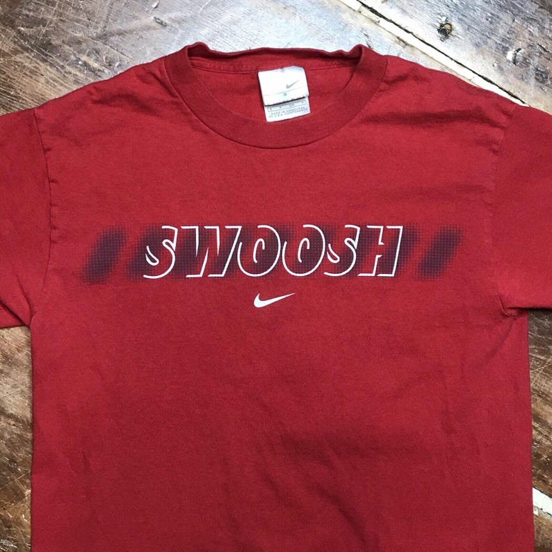 May include: Red t-shirt with a white "SWOOSH" graphic and a small Nike logo.