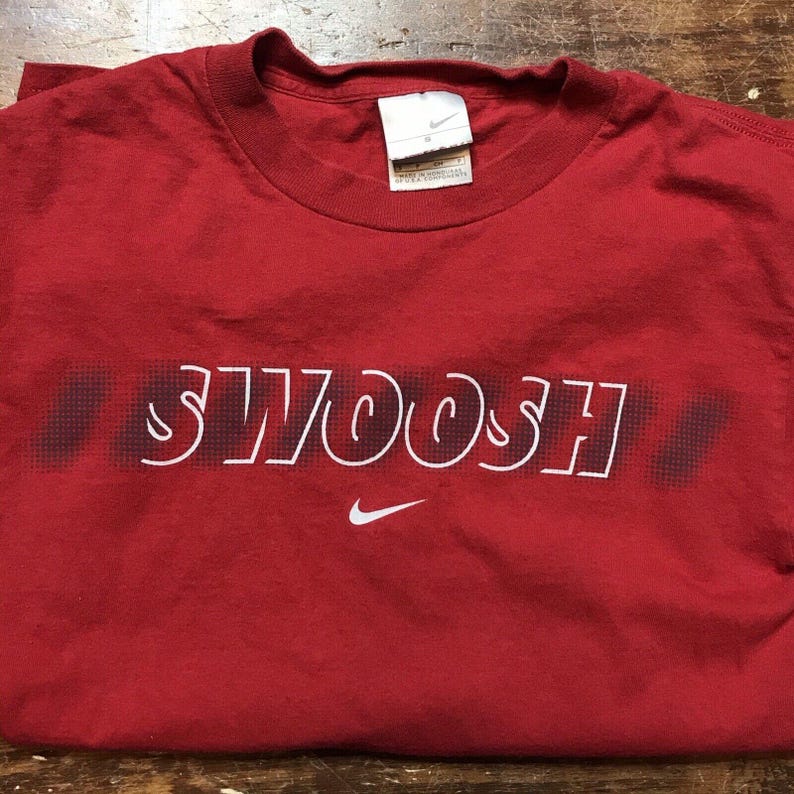 May include: Red t-shirt with a white "SWOOSH" graphic and a white Nike logo.
