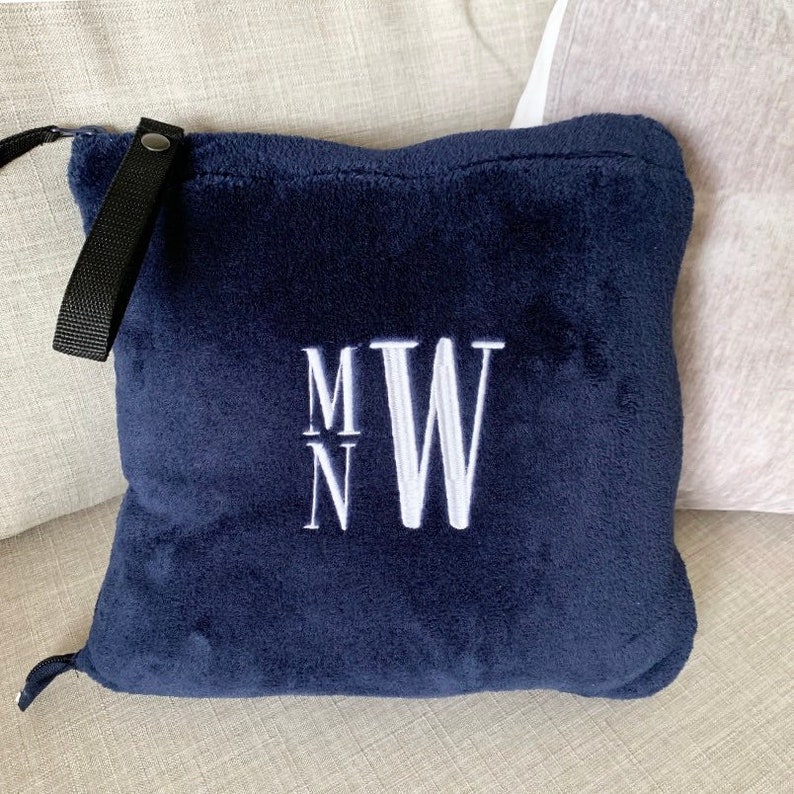 K&ouml;nnte beinhalten: Ein dunkelblaues Fleece-Wurfkissen mit einem wei&szlig;en gestickten Monogramm "M N W".