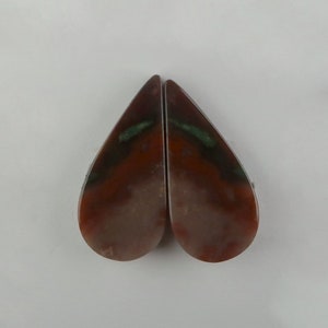 May include: Two teardrop-shaped pieces of agate with brown, white and green patterns.