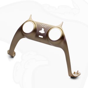 Op de afbeelding: Een gouden plastic controller-behuizing met twee ronde uitsparingen en een kleine rechthoekige uitsparing. De behuizing heeft aan elke kant een kattenoor-ontwerp.